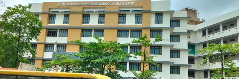 The school and Jr. College building: a multi-storey block in cream and ochre bands with the sign ‘Fr. Agnel Multipurpose School & Jr. College’ across the top, trees in front and a yellow school bus along the bottom edge.